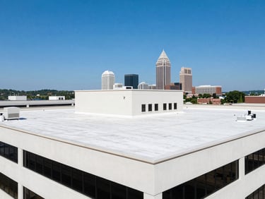Large commercial building with a newly installed flat roof, bright daylight, clean lines, Huntsville skyline in background