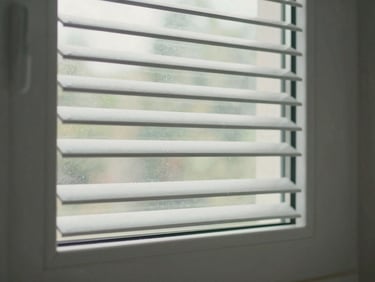 Environmental photograph of a UPVC louvre window with angled glass blades in an Indian bathroom wall, diffused natural light filtering through the angled slats, white UPVC frame intact