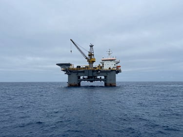 Wide panoramic shot of an offshore construction vessel at sea under cool overcast daylight, heavy subsea crane visible, deep blue water