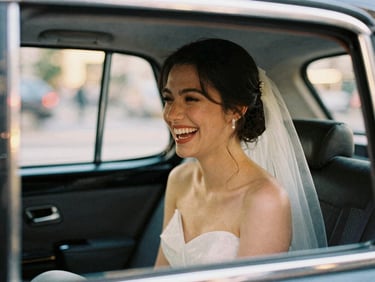 Candid close-up of a bride laughing in the back of a vintage taxi, soft city lights, 35mm film aesthetic