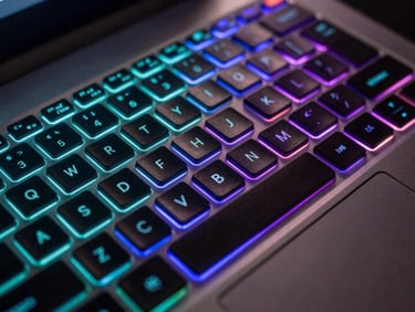 Close-up macro of a premium gaming laptop keyboard with per-key RGB illumination glowing cyan and purple, dark environment, neon light refraction on brushed aluminum chassis
