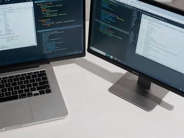 A top-down macro shot of a modern clean workspace, dual monitors displaying technical system schematics and database code, sharp cool daylight lighting, crisp shadows.