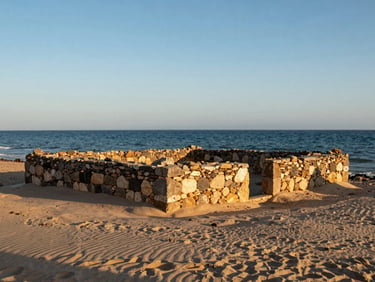 Ancient stone tonnara ruins on the edge of a quiet coastal lagoon in Vendicari, warm late afternoon sun