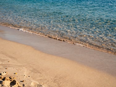 Sun-drenched sandy beach with crystal clear turquoise water in Sicily, golden hour light, soft shadows