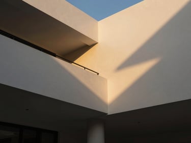 Low-angle architectural shot of a luxury Riyadh villa interior, pristine painted walls catching dramatic side golden hour sunlight, sharp focus, 35mm lens