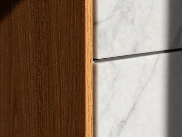 Macro close-up of a flawless wall transition between warm textured wood panels and a polished white marble alternative, sharp focus on the crisp clean seam, dramatic side-lighting, premium architectural detail