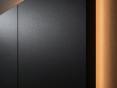 Close-up of a flawless matte dark paint texture on a modern wall, subtle architectural side-lighting, premium architectural photography.