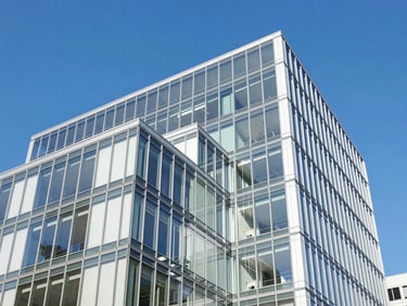 Abstract high-contrast architectural shot of a modern financial center facade, bright blue sky reflecting on clean glass panels