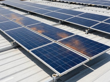 Crisp industrial photography of a large-scale solar array on an industrial roof under bright natural sunlight, high-contrast blue and amber tones, sharp focus, 35mm lens.