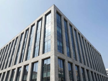 Wide-angle exterior photograph of a modern commercial concrete and glass building, clean geometric lines, bright daylight reflecting off glass windows.