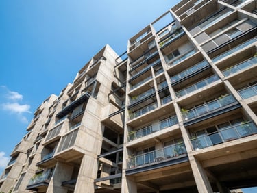 Low-angle architectural shot of a modern concrete and steel residential building facade in Visakhapatnam, bright midday sun highlighting structural geometry, clean blue sky