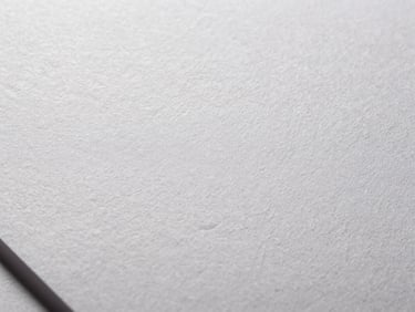 Extreme close-up of embossed white paper texture with crisp shadows, high-contrast directional studio lighting, 50mm