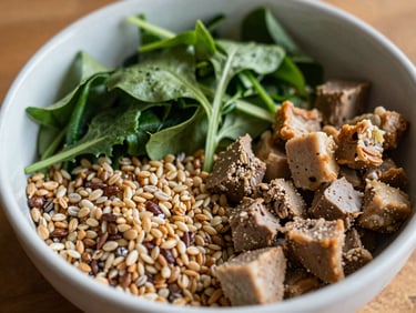 Overhead shot of a vibrant bowl of whole grains, leafy greens, and lean protein, warm ambient indoor light, shallow depth of field.