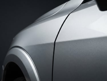 Crisp close-up of a metallic silver car fender with perfect panel gaps, high-contrast studio lighting, deep gray background, sharp details, 50mm