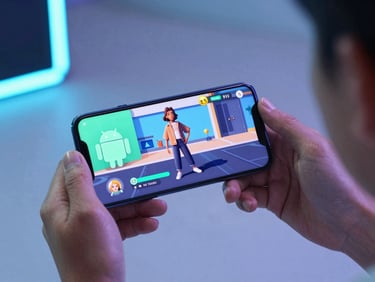 Over-the-shoulder perspective of a hand holding an Android phone displaying a vibrant casual game with neon mint accents. Cool ambient studio lighting, sleek tech photography, shallow depth of field.