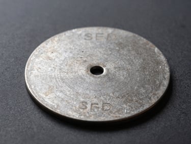 Makroaufnahme einer leeren Stahlplatte für Seed-Phrasen, die auf einem dunklen, strukturierten Hintergrund liegt, scharfes Studio-Licht, vermittelt Leere und Risiko.