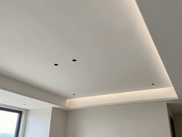 Interior view of a living room with a contemporary false ceiling design and integrated recessed lighting, wide environmental shot, well-lit interior space
