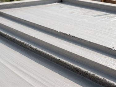 Close-up of multi-layer waterproofing application on a terrace, showing different material layers, bright natural daylight, technical angle.