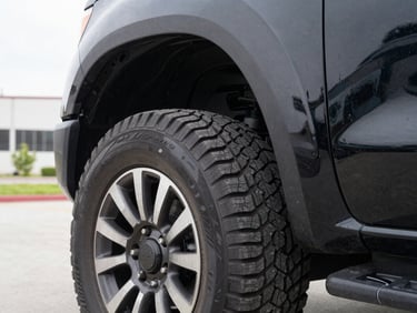 Detailed shot of a clean black pickup truck tire tread and wheel well, bright overcast daylight