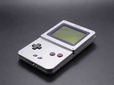 A silver Game Boy Advance SP console partially folded on a clean workbench, soft shadows, sharp macro focus.