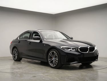Three-quarter front angle of a black BMW 3 Series on a matte concrete studio floor, bright overhead studio lighting, clean neutral backdrop, no people