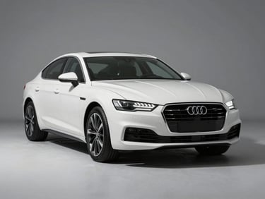 Three-quarter front angle of a white premium sedan on a clean light-grey studio floor, studio strobe lighting casting subtle shadows beneath the vehicle, sharp detail on grille and headlights, no people