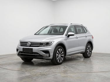 Three-quarter front angle of a silver Volkswagen Tiguan on a matte concrete studio floor, bright neutral studio lighting, clean white backdrop, no people