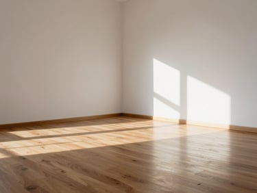 Sunlit empty room with clean hardwood floors and white walls, architectural shadows