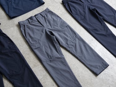 Crisp flat-lay of technical teamwear kits on a concrete background, bright cool-toned studio light, sharp focus on reinforced double-stitched seams.