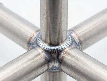Close-up studio shot of a pristine welded titanium joint, clean high-exposure lighting, sharp focus on the uniform bead, 50mm