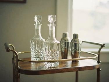 Vintage wooden bar cart with crystal decanters and silver shakers, soft golden light, shallow depth of field