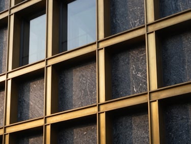 Close-up of premium architectural materials, textured stone, and gold metal accents on a modern building facade.
