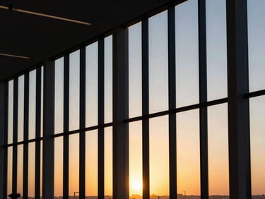 Modern commercial office suite interior with floor-to-ceiling windows, warm sunset light, minimalist layout, luxury architectural photography