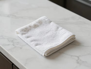 Overhead shot of a polished white marble countertop with a clean, dry microfiber cloth resting on its immaculate surface.