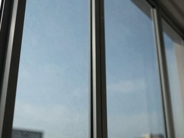 Close-up macro shot of a spotless, streak-free glass window pane reflecting bright natural daylight, geometric frame.