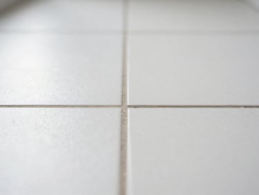 Macro straight-on shot of a sterile, clean white tile surface with pristine grout lines, clinical natural daylight.