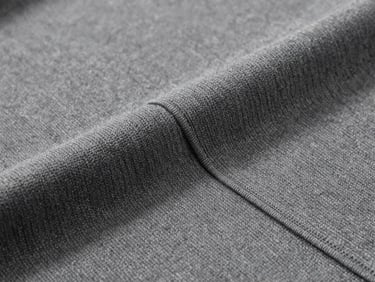 Extreme close-up of charcoal technical knit fabric weave, showing heavy-gauge texture and clean seam construction, soft diffused overcast daylight.
