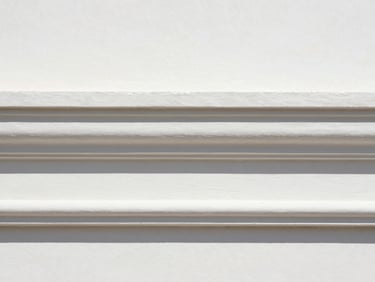 Close-up detail of a crisp paint transition on an architectural wall molding, sharp contrast, perfect clean edge, professional editorial style.