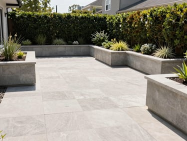 A clean modern backyard stone patio with custom concrete masonry planters, manicured architectural plantings, bright daylight, sharp lines.