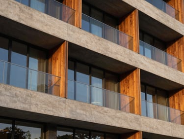 Detail of a luxury hotel facade with concrete and warm wood elements, sunset light reflecting on glass, clean architectural lines