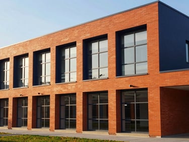 Modern school campus building with large windows and geometric brickwork, morning light, clean structural design
