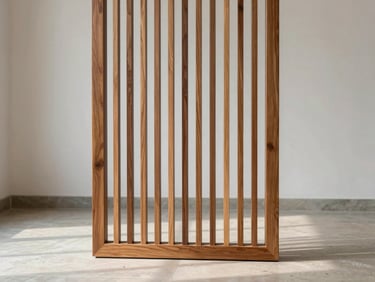 Solid teak wooden room partition standing in an empty interior under even daylight, geometric slat pattern casting soft shadows on a pale stone floor, white walls behind