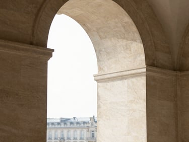 Warm editorial photography of a limestone archway in Paris, clean architectural lines, soft natural morning shadows, 35mm.