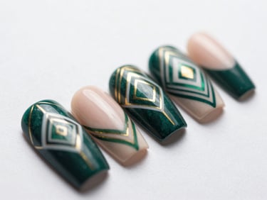 Close-up macro shot of five finished nail-art designs — intricate geometric patterns in deep emerald, blush, and gold on a cream background, isolated nail tips fanned out on white surface, bright diffused daylight, pigment and finish detail sharp