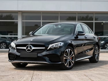 Wide three-quarter front shot of a black 2018 Mercedes-Benz C-Class on a neutral dealership forecourt, bright daylight, full vehicle visible