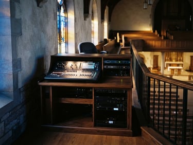 A clean, modern soundboard and audio rack neatly integrated into a church balcony, warm ambient lighting, sharp focus, 35mm