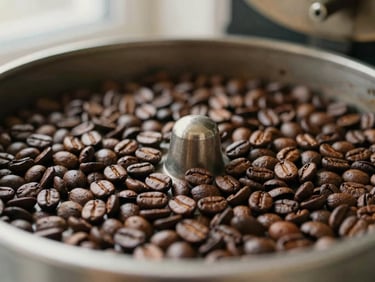 Close-up of roasted coffee beans cooling in a roasting machine tray, rich brown textures, soft warm lighting, shallow depth of field