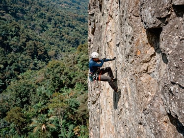 Climber rappelling down a steep canyon wall in Zapopan, harsh natural light, technical gear visible