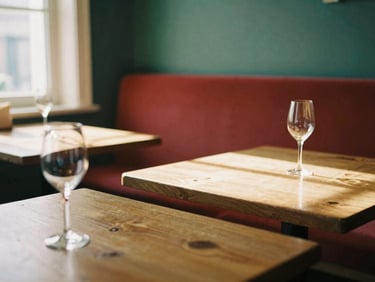 Cozy Scandinavian-style restaurant interior with warm timber tables, soft window light casting moody shadows, wine glass in foreground, 35mm film