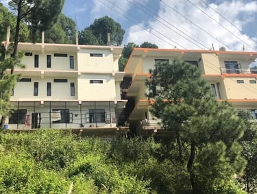The exterior of the multi-story Mehar Rehabilitation Center building nestled in the green trees.